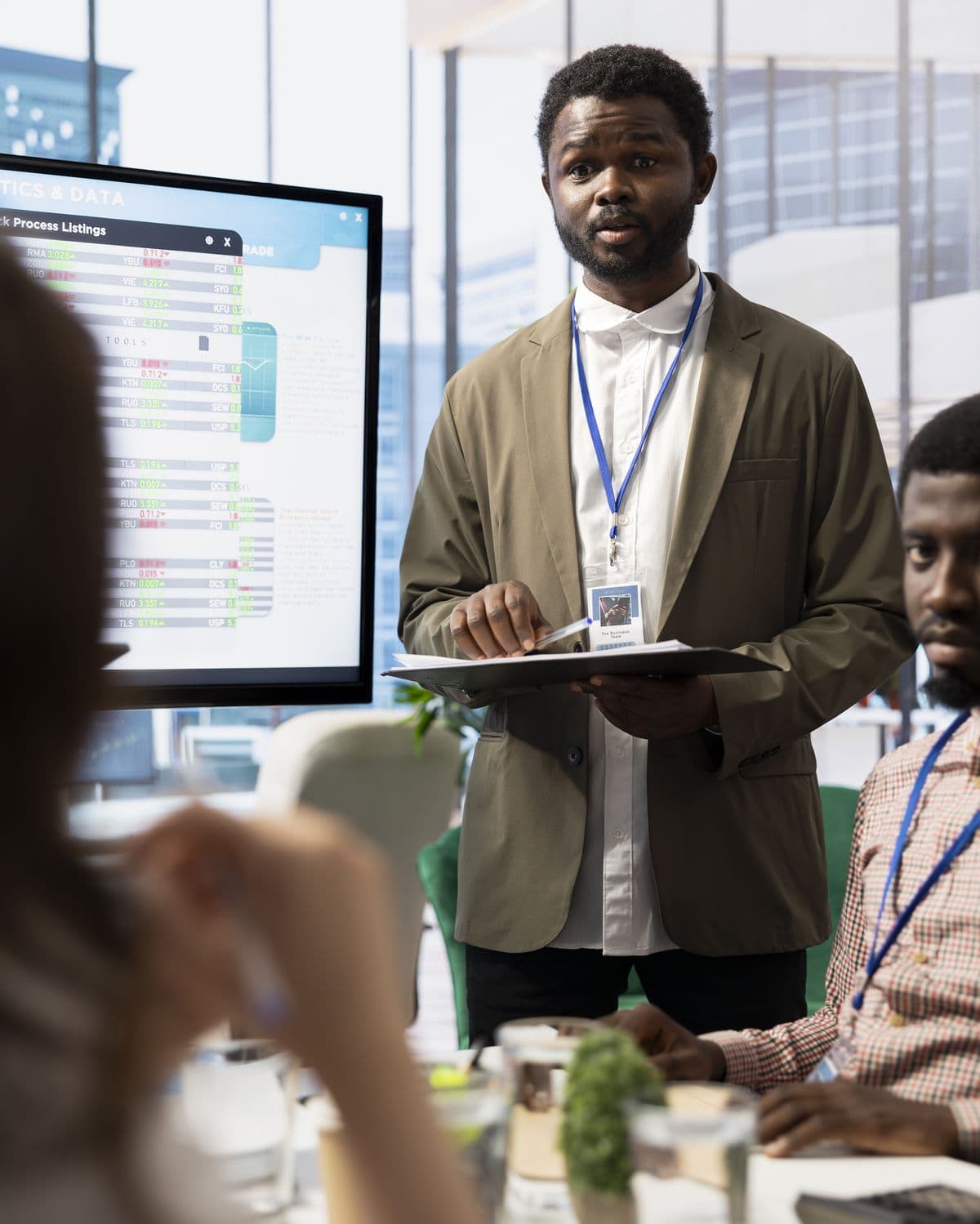 A manager briefing colleagues in a corporate meeting room.